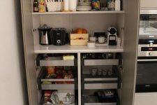 a built-in pantry with open shelves and drawers, with appliances, tableware, various cups, mugs and other stuff