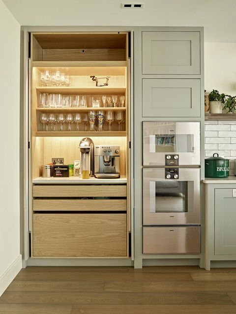 a built-in pantry with open shelves and lights, drawers of various sizes, appliances and lots of wine jars