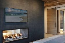 a chalet fireplace witha reclaimed wood ceiling, a bed, a double-sided metal clad fireplace and some artwork