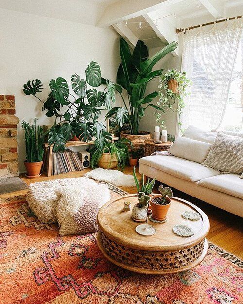 a cheerful boho living room with a white sofa, a bold boho rug, a lot of potted plants, a wooden coffee table