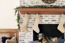 a chic whitewashed brick fireplace with a wooden stained mantel, baskets, candle lanterns and stockings for Christmas