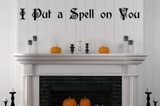 a classic Halloween fireplace with orange, black and white pumpkins, letters and candles is chic