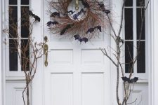 a classic Halloween porch with pumpkins and a vine wreath with bats and branches is spooky and cool