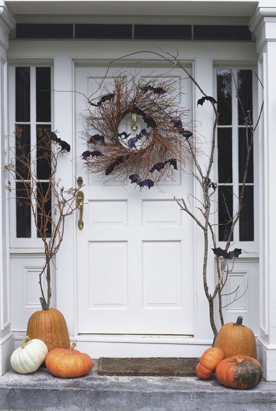 a classic Halloween porch with pumpkins and a vine wreath with bats and branches is spooky and cool