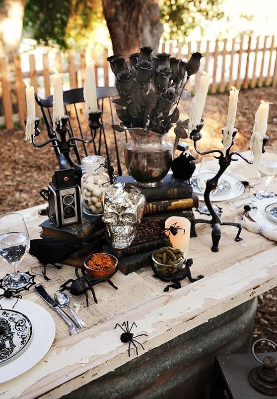 a classic Halloween tablescape with black roses, skulls, eyeballs, bugs, pillar candles and black and white porcelain
