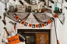 a colorful Halloween fireplace with a bold garland, lots of natural and faux pumpkins, printed pillows, black spider web, black bats on the wall