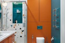 a colorful bathroom with blue and orange touches, terrazzo and white appliances and built-in lights