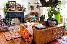 a colorful boho living room with a fireplace, a mustard sofa, bright rugs and pillows, potted plants and bold artwork