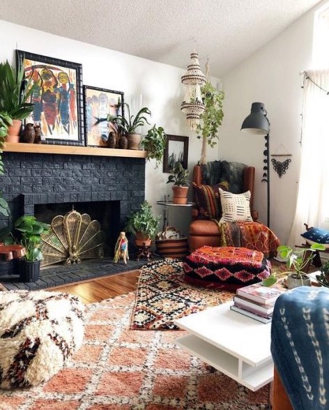 a colorful boho living space with a black brick clad sofa, a leather chair, boho ottomans and pillows, a chandelier and bright artworks