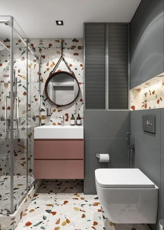 a contemporary bathroom with bright terrazzo walls and a floor, grey tiles, a mauve vanity and white appliances