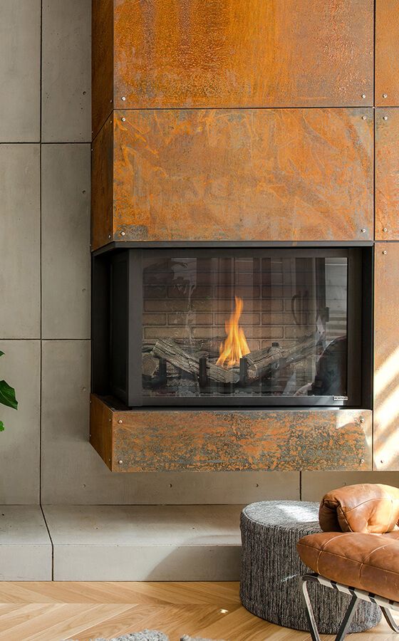 A copper clad built in fireplace, a leather chair and a pouf compose a super cozy and welcoming nook