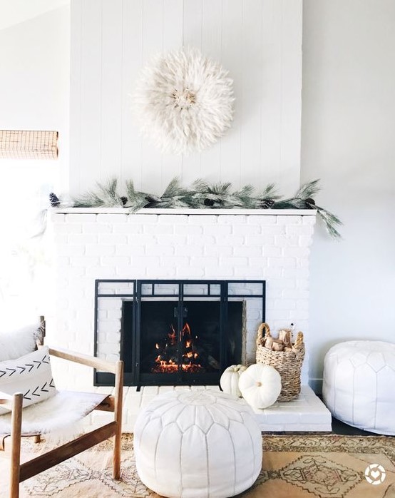 a cozy farmhouse living room done in white, with a white brick clad fireplace to add texture