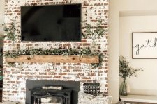 a farmhouse shabby chic fireplace with a wooden mantel covered with greenery, a woven basket and antlers