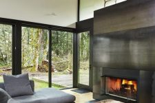 a fireplace clad with blackened steel separates the living room from the covered patio and brings coziness to the space
