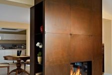 a fireplace clad with copper, with firewood storage and some blooms will become a focal point in the space