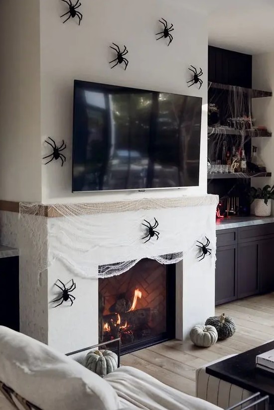 a fireplace covered with faux spiderweb and black spiders, a couple of heirloom pumpkins is a gorgeous idea for Halloween