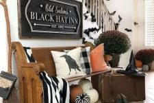 a gorgeous Halloween entryway with large pumpkins, black and white fabric, a witch broom, hat, shoes and some bats