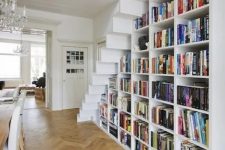 a large bookcase built under the stairs is all you need to save the space and acomodate them all