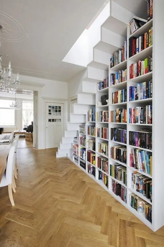a large bookcase built under the stairs is all you need to save the space and acomodate them all