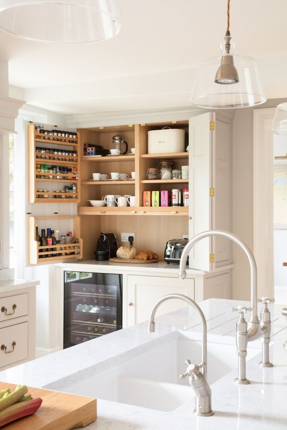 A large built in pantry with open shelves, shelves on the door, some appliances, tableware and jars is a cool solution