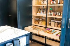 a large built-in pantry with open shelves that store food in jars, oils and spices, drawers with food and cookies