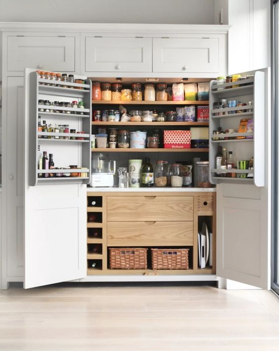 A large built in pantry with stained shelves, drawers and baskets plus some shelves on the doors