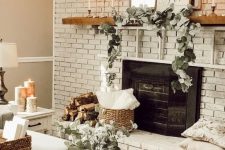 a large whitewashed brick fireplace, a stained mantel with greenery, a mirror and art plus candles