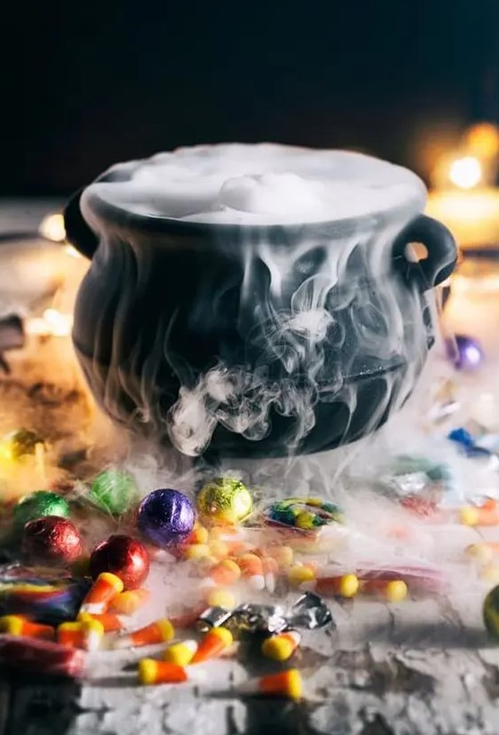 a lovely Halloween decoration of a black cauldron with smoke and lots of sweets around is easy to make and looks cool