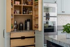 a lovely built-in pantry that matches the kitchen, with stained drawers, shelves and built-in lights