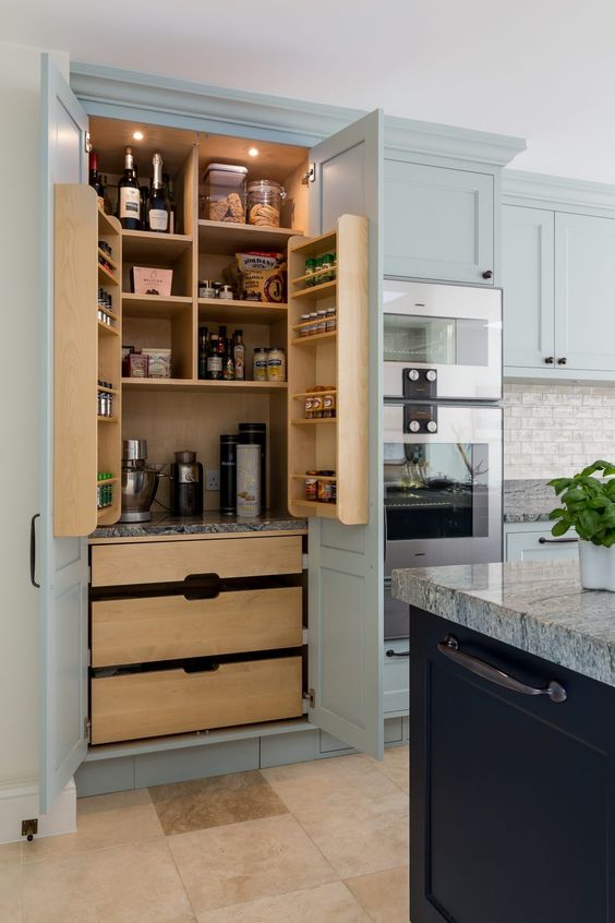 a lovely built-in pantry that matches the kitchen, with stained drawers, shelves and built-in lights