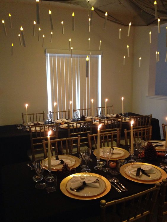 a magical Harry Potter Halloween table setting with black linens and gold chargers, floating candles and fruit as centerpieces