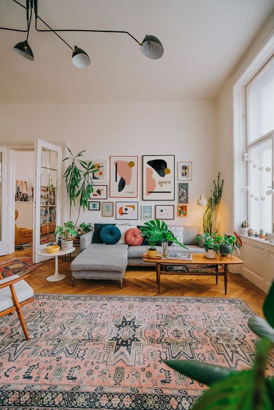 a mid-century meets boho living room with a grey sofa, a coffee table, a chair, a boho rug and a bright gallery wall