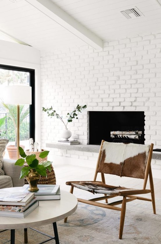 A mid century modern fireplace clad with whitewashed brick, with a stone bench under it instead of a mantel, stylish modern furniture