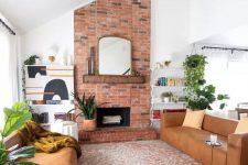 a mid-century modern living room with a red brick fireplace, amber leather sofas, greenery and open shelves
