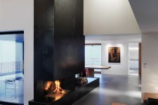 a minimal space with a black metal clad fireplace, a black sofa and a stained coffee table is amazing
