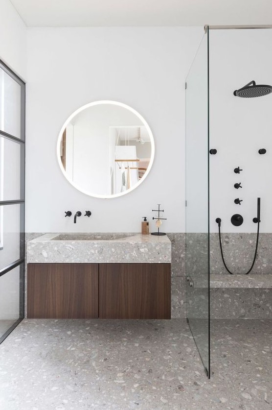 A minimalist bathroom in neutrals is made eye catchy with grey terrazzo on the floor and countertops and black fixtures