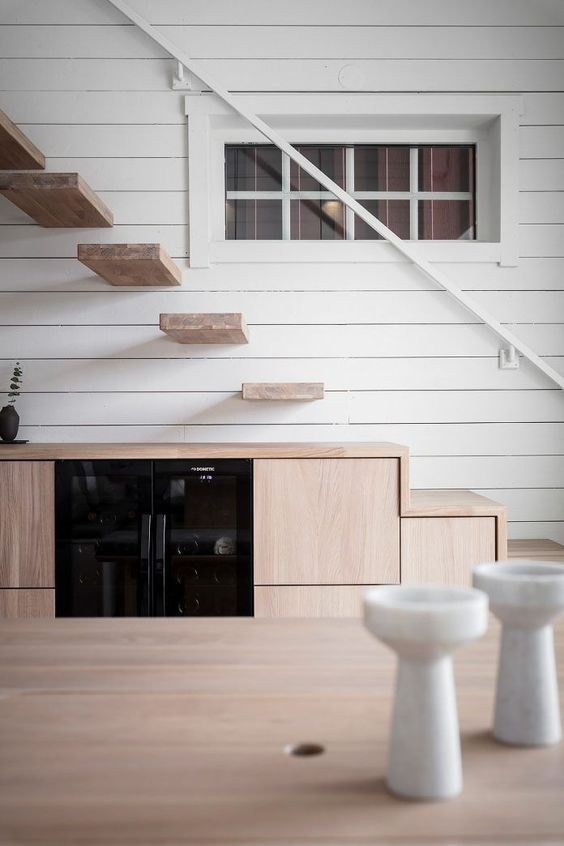 a minimalist stained kitchen built in under the stairs, floating steps over it create a very lightweight look
