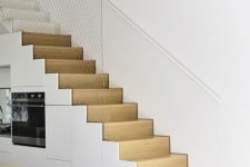 a minimalist white kitchen completely built into the staircase is a smart solution if you don’t have space for a kitchen
