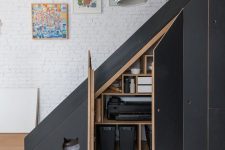 a modern black staircase with built-in storage compartments with doors and a small entrance to the pet house