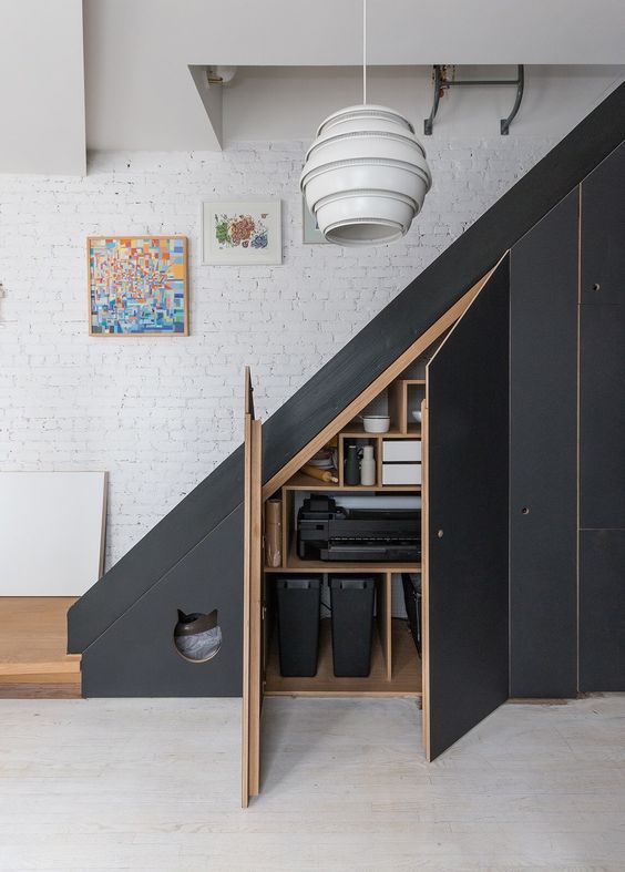 A modern black staircase with built in storage compartments with doors and a small entrance to the pet house