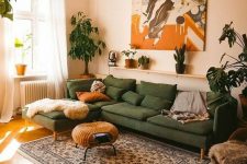 a modern boho living room with a green sofa with pillows, a woven coffee table, a bold artwork, a printed rug and some potted plants