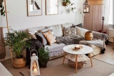 a modern boho living room with a sectional, a coffee table, some potted greenery and artwork, a pendant lamp