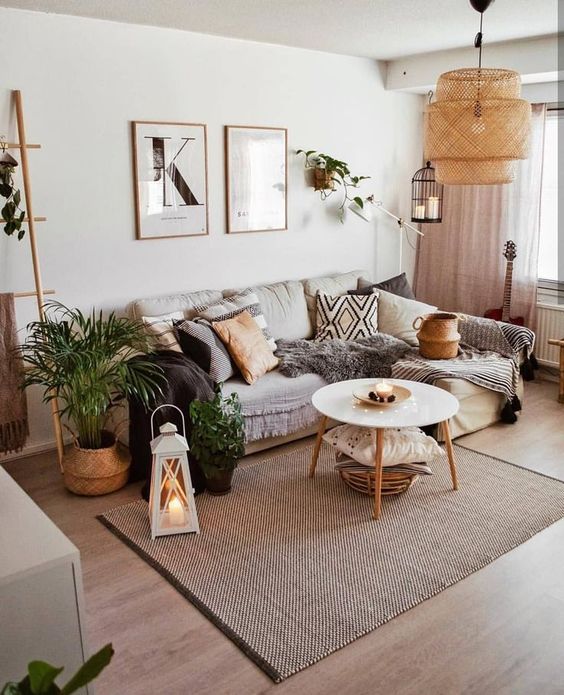 a modern boho living room with a sectional, a coffee table, some potted greenery and artwork, a pendant lamp