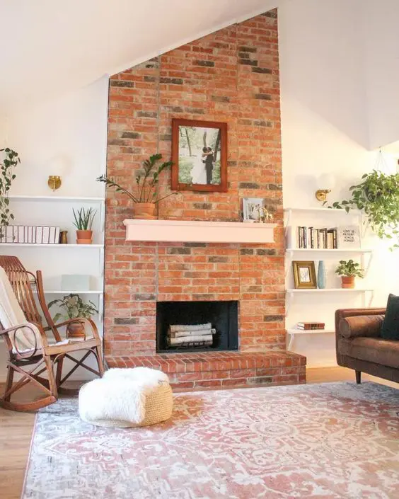 a modern living room with a red brick fireplace, a brown leather sofa, a rocker chair and open shelves