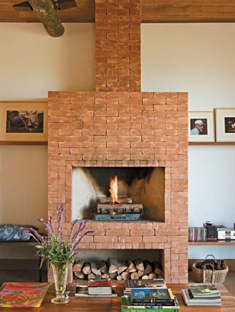 a modern space with a red brick fireplace and firewood storage plus benches on both sides of the fireplace