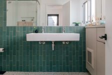 a pretty bright bathroom with turquoise skinny tiles and grey and white terrazzo flooring, white appliances and a large mirror