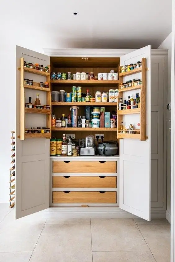 a pretty pantry built into the kitchen cabinets, with shelves, drawers and lots of food, oils, spices and various appliances