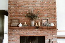 a red brick fireplace with a rich-stained mantel, a modern and chic firewood stand, lovely decor on the mantel is cool