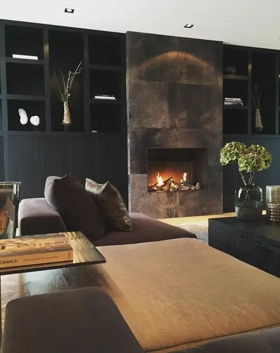 A refined moody living room with a built in fireplace clad with a dark metal surround that adds glam and chic to the space
