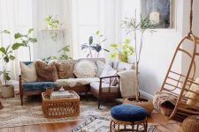 a relaxed boho living room with a sectional, pillows, printed rugs, a coffee table, potted plants and a pendant chair